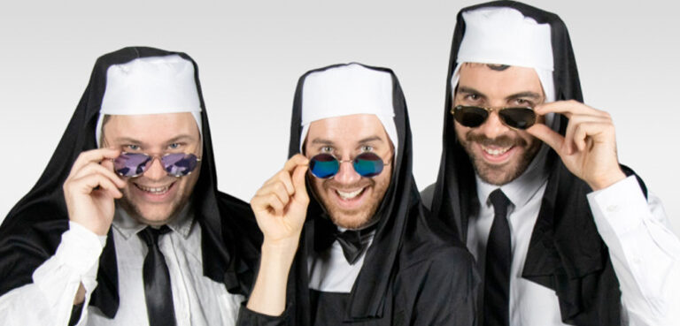 Three people (two of whom have full facial hair) wearing nun's habits and white business shirts and black satin ties hold the rim of their aviator sunglasses with one hand while peeking over the glasses and smiling cheekily.