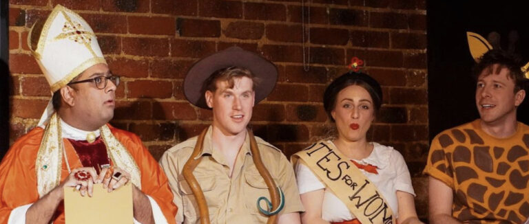 A mid-scene image of four comedians in full costume doing celebrity impersonations, from left to right: Pedro Cooray as Pope Benedict IX, Riley Nottingham as Robert Irwin, Belinda Anderson-Hunt as Mary Poppins and Charlie Lewin as Healthy Harold